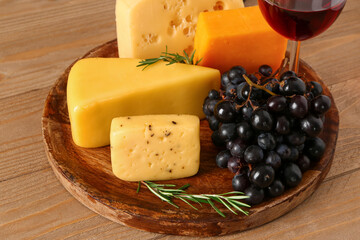 Plate with tasty cheese and grapes on wooden background