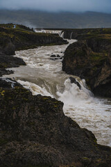 Obraz premium Fast river going down the road. Beautiful view of the waterfall 