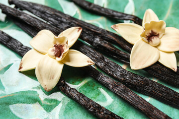 Aromatic vanilla sticks and flowers on green background