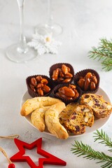 Assorted Christmas cookies and sweets on a round plate on a light concrete background in Christmas style. Merry Christmas concept.