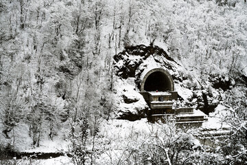 Winter mountain landscape. Tunnel under construction through a mountain, trees and bushes in the snow on mountain hills in Georgia