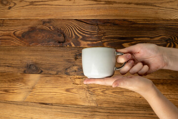 Hand Holds Cup, Empty Cup in Hands, Coffee Mug, Teacup Mockup, Cup in Arms on Wooden Table