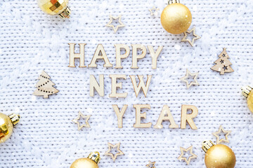 Happy New Year wooden letters on cozy festive white knitted background with sequins, stars, lights of garlands. Greetings, postcard. Calendar, cover
