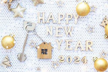 House key with keychain cottage on cozy festive knitted background with stars, bokeh. Happy New...