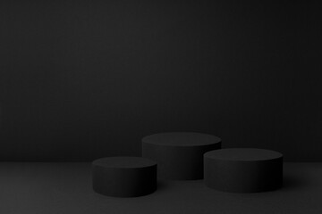 Abstract black scene with three cylinder podiums template for presentation cosmetic products, goods, advertising, design, poster, text, card. Black stage template in rich contemporary minimal style.
