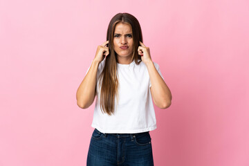Young Uruguayan woman isolated on pink background frustrated and covering ears - obrazy, fototapety, plakaty