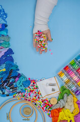 Hands of woman embroidering on cloth at studio. Womans hands choosing embroidery thread.