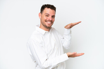 Young caucasian handsome man isolated on white background holding copyspace to insert an ad
