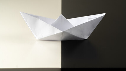 
a white paper boat lies on a black and white background