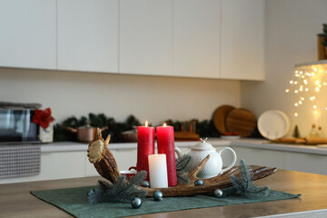 Moose antler with burning candles, Christmas branches and teapot on table in kitchen