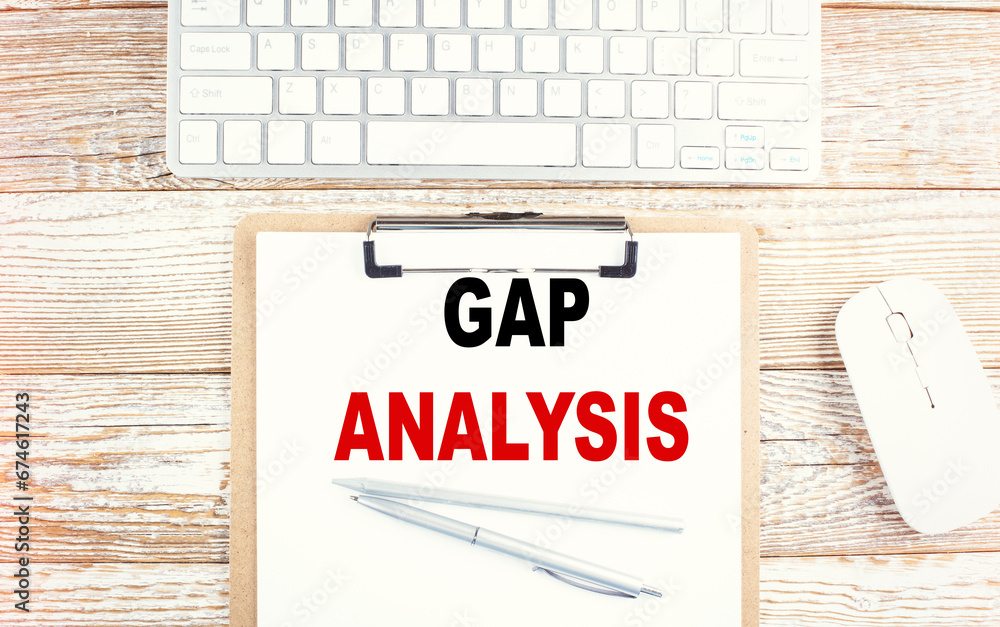 Poster gap analysis text on paper clipboard with keyboard on a wooden background