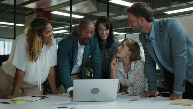 Group of happy multiracial business people in businesswear talking next to laptop during corporate meeting