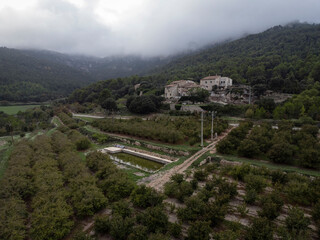 Aerial View of Hazelnut Grove with Farmhouses, Forest, and Misty Mountains in 'Bosquet,' Tarragona"