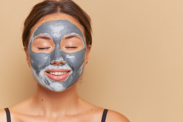 Close-up shot of woman isolated over background with closed eyes and with clay facial mask, skincare routine concept, copy space