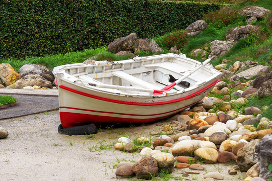 Empty rowing boat on a picturesque shore with rocks and vegetation