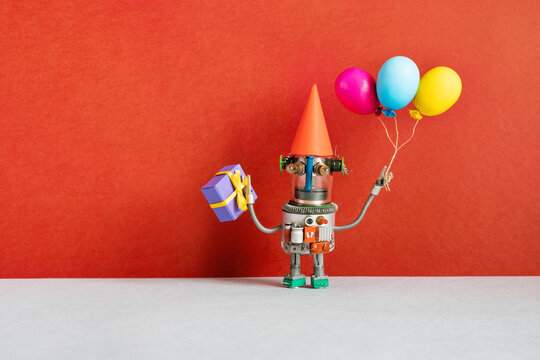 A festive greeting card for any event or birthday party. A happy robot holds gift box, yellow blue violet balloons.