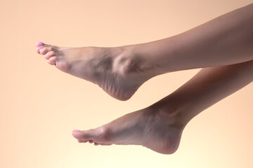 Closeup bare female feet on a beige background