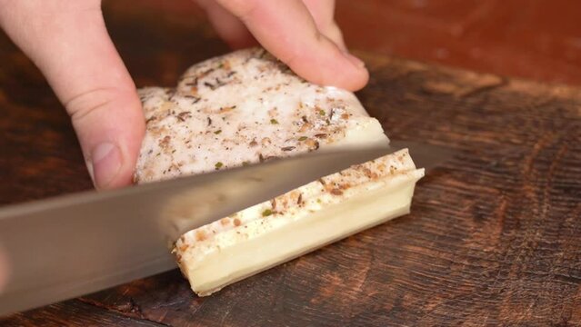 Slicing of salted pork fatback on cutting board, close-up. Ukrainian traditional food - salo	
