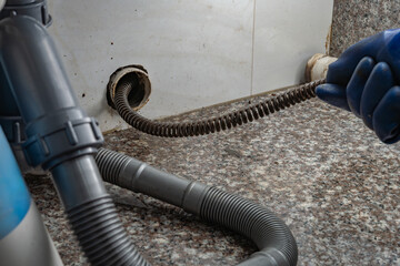 plumber using equipment to remove grease from the drain pipe