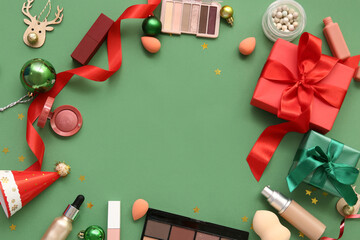 Frame made of different makeup products and Christmas decor on green background