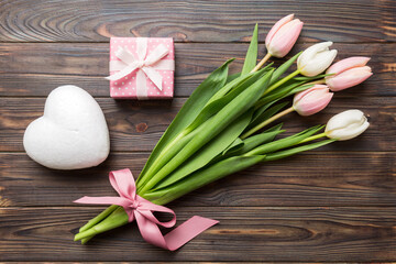 Pink tulips flowers and gift or present box on colored table background. Mothers Day, Birthday, Womens Day, celebration concept. Space for text top view