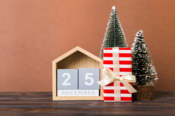 Fototapeta na wymiar 25 december. Christmas composition on colored background with a wooden calendar, with a gift box, toys, bauble copy space