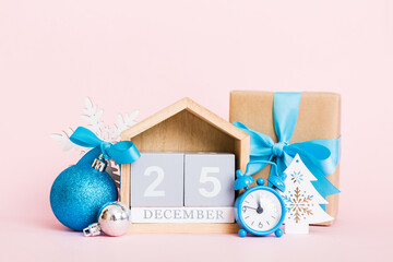 25 december. Christmas composition on colored background with a wooden calendar, with a gift box, toys, bauble copy space