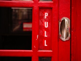 Red telephone booth pull door in Britain 