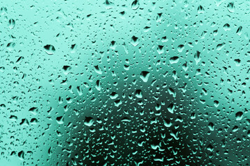 Obraz premium Water drop on glass on a green background.