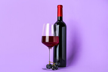 Glass and bottle of exquisite wine on lilac background