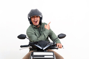 Excited asian man pointing sideways while riding motorcycle. Isolated on white background