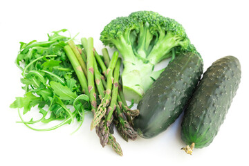 Still life from green farm vegetables, arugula, broccoli, asparagus and cucumbers on white background