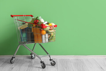 Shopping cart full of food near green wall