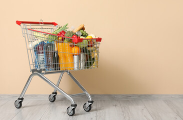 Shopping cart full of food near beige wall