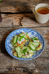 Draniki with cream cheese and cucumber on a blue plate. Top view, wooden background