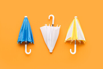 Mini stylish umbrellas on orange background © Pixel-Shot