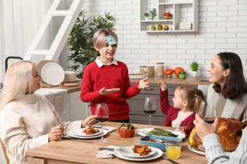 Happy family playing word guessing game at festive table on Thanksgiving Day