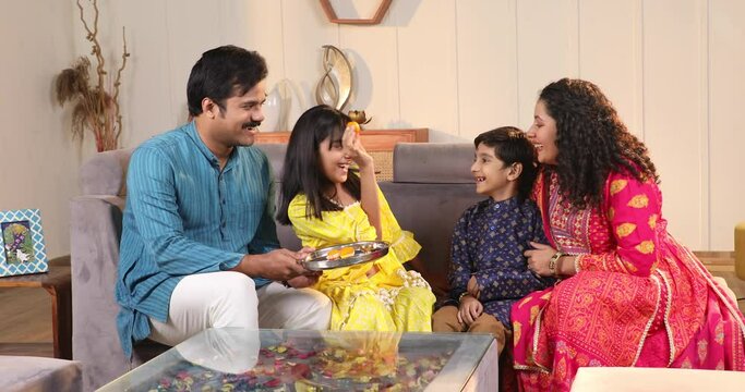 Girl giving her brother bite of laddu on Rakshabandhan
