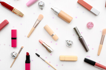 Different decorative cosmetics with Christmas balls and confetti on white background