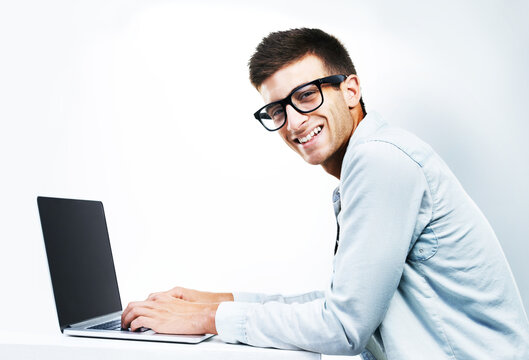 Portrait, business man typing on laptop at table and isolated on white background. Face, smile and geek at desk on computer, technology and IT programmer in glasses, coding and mockup space in Canada