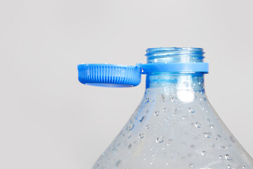 Close up of new cap attached to plastic bottle, connected to the neck of the bottle by solid tab attached to safety ring. They are intended to encourage recycling, as part of the fight against litter. - obrazy, fototapety, plakaty