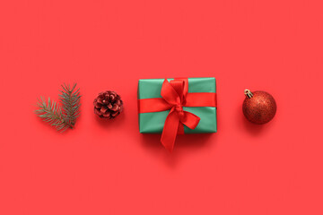 Christmas gift box with fir branch, cone and ball on red background