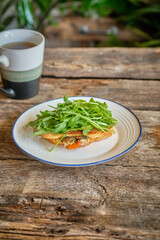 hot sandwich with arugula. wooden background.