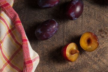 Whole and half of purple plums on wooden background. .