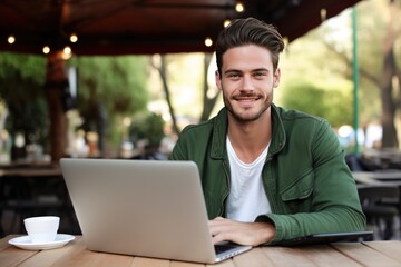 Obraz premium Smiling man using his laptop at an outdoor cafe