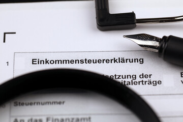 German annual income tax return declaration form blank on A4 tablet lies on office table with pen and magnifying glass close up - obrazy, fototapety, plakaty