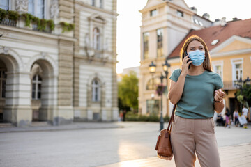 Business woman with protective mask talking on phone outdoor.