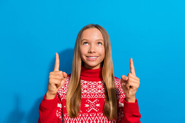 Photo of optimistic nice adorable schoolgirl dressed red sweater directing look at offer empty space isolated on blue color background