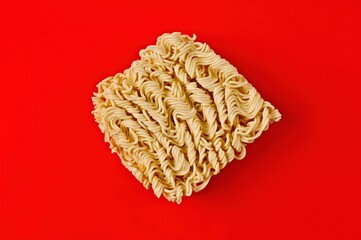 Block of instant ramen noodles on red background.