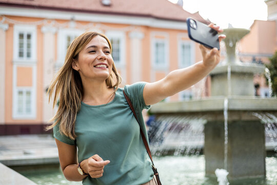 Travel, selfie and young woman in a city, happy and smile on vacation against urban background. Blog, social media and girl influencer live streaming trip in city for online, followers or network.